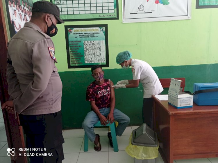Bhabinkamtibmas Polsek Paga Lakukan Pengamanan Vaksinasi Dosis I dan II di Puskesmas Feondari
